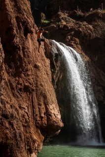 OUZOUD, MOROCCO - OCTOBER 5, 2024: A Moroccan young boy jumps from the high rock into the water