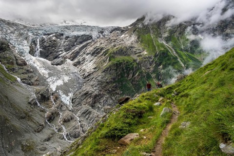 Two mountaineers on a hiking trail, cloudy mountain landscape with Grindelwald-Fiescherfirn