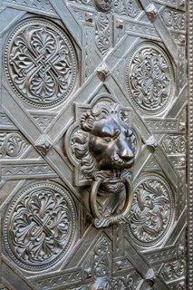 Artfully decorated bronze door with lion's head as a door puller or door knocker on the Gallus