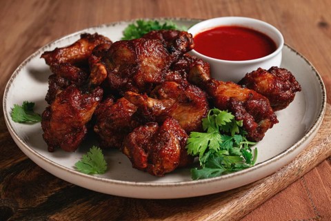 Juicy fried chicken pieces, served with spicy dipping sauce, on a rustic wooden table
