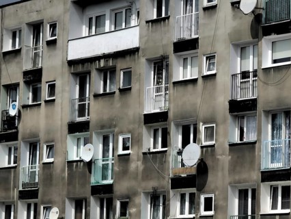 Façade, urban apartment block with numerous windows and satellite dishes on grey walls, Wroclaw,