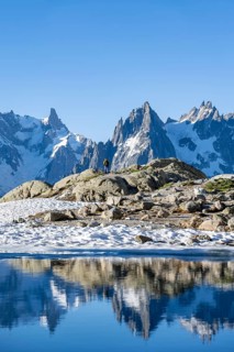 Young man in front of impressive mountain landscape in morning light, reflection in the Lac Blanc