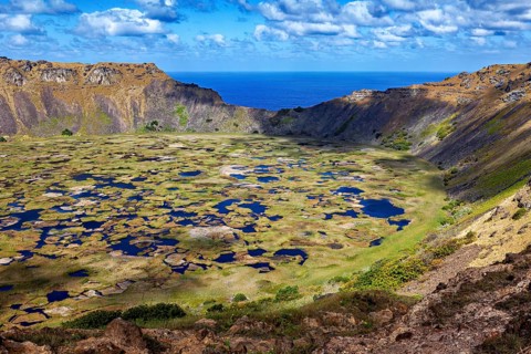 A large crater basin with small water pockets surrounded by a sublime volcanic landscape, the Ranu
