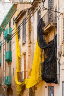 Yellow and black safety nets at the construction site of a house in Carrer de Sant Pere, Palma de