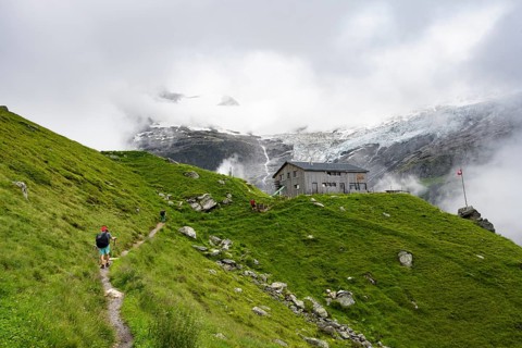 Hikers on a hiking trail at Berghaus Bäregg mountain hut, cloud-covered mountain landscape with