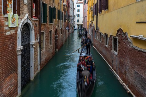 Gondola ride with tourists through the old town of Venice, Veneto, Italy