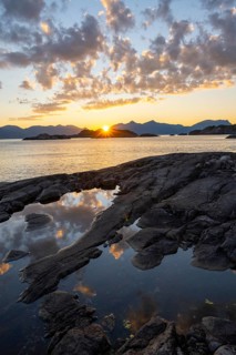 Clouds reflected in a small pond on a rocky coast, coastal landscape at sunset, Henningsvær,