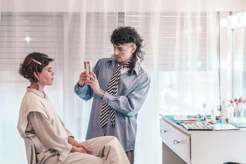 Makeup artist taking pictures of model's face with smartphone after finishing makeup session in