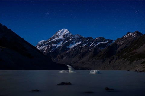 Mountainous landscape. Hooker Lake and Aoraki Mount Cook. At night, starry sky. Aoraki Mount Cook