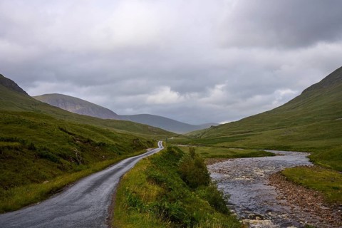 Landscape with a road and a passing river surrounded by green hills and clouds, Glen Etive,
