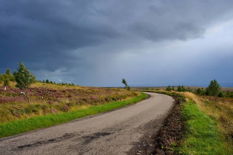 Curvy road in a landscape under a menacingly cloudy sky, Lairg, Scotland, United Kingdom, Great