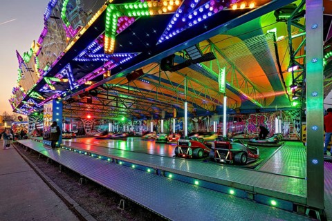 A colorful bumper car course at a fair at dusk, carousel and the hustle and bustle of summer profit