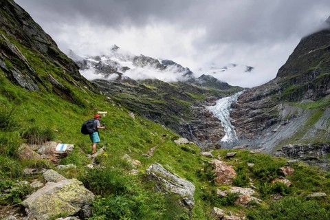 Mountaineers on a hiking trail, cloudy mountain landscape with Lower Arctic Sea glacier, Bernese
