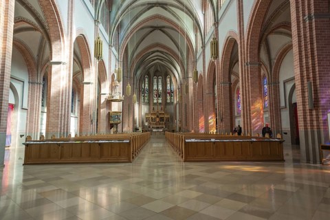 Further view through the interior of a church with high ceilings and long benches, Herz Jesu