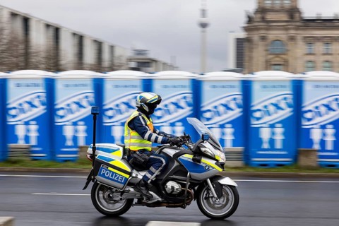 Reichstag Berlin with waving flags. Before that, mobile toilets for a major event. Police