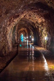 A long tunnel with a wet floor. The tunnel is dark and the lights are on. The water on the floor