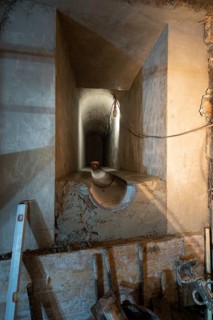 A partially constructed underground tunnel with visible concrete supports and unfinished surfaces.