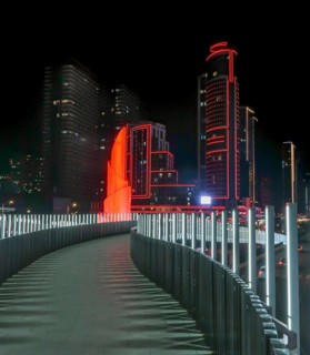 Night view of a modern cityscape in Georgia, featuring a brightly illuminated skyscraper adorned