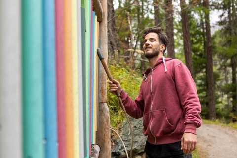 A man in a hoodie enjoys a serene moment in an autumn forest in Switzerland. The colorful foliage
