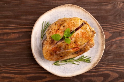Fried Turkey Thigh with spices and rosemary on plate on brown wooden background. top view, flat