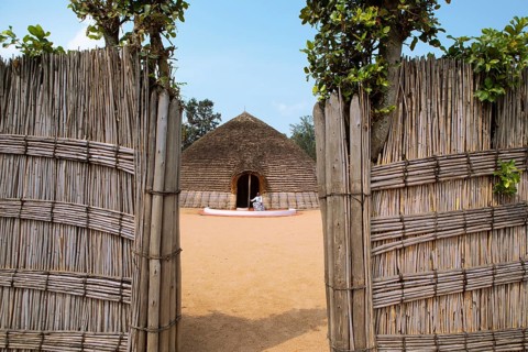 Rwandan man, 25 years old, wearing traditional dress at the entrance to the Royal Palace replica in