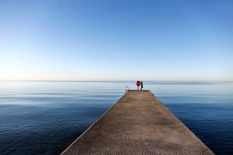 Northern lights, atmosphere with soft blue as far as the horizon, a woman standing on a jetty on