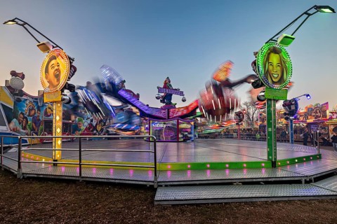 A spinning ride with colorful lights and blurred movements at dusk, carousel and the hustle and