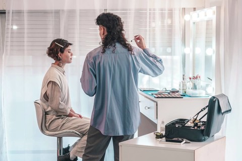 Professional makeup artist applying cosmetics on a model in a bright, modern beauty salon,