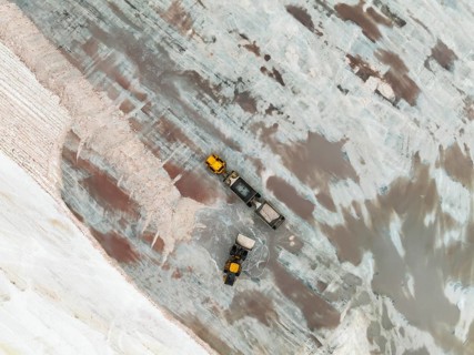 Excavator and lorry at a harvesting pan of the Walvis Bay Salt works. Aerial view. Drone shot.