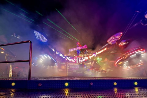 A carousel wrapped in fog at night, illuminated by colorful neon lights in motion, carousel and