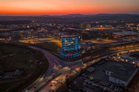 Panoramic view of the city with an illuminated skyscraper at dusk, Porsche, Bietigheim, Germany