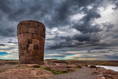 A large stone tower against a dramatically cloudy sky, The Chullpas of Sillustani near Puno in Peru