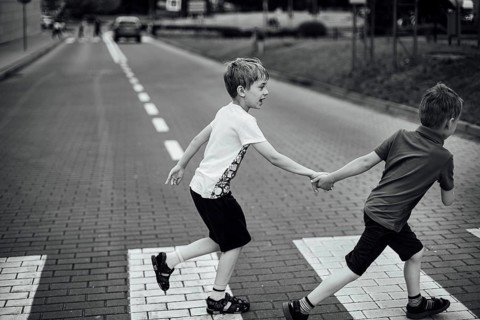 Two boys walk the pedestrian crossing on the street
