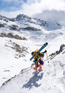 Mountaineer with skis climbing up a steep snow slope to the fork Porta d'Es-cha, ski tour Bündner