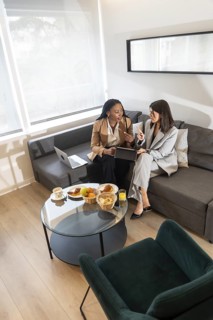 Two businesswomen are having breakfast and discussing work in their hotel room during a business