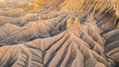 Warm sunlight bathes the intricate landscape of Caineville Mesa near Hanksville, Utah, highlighting