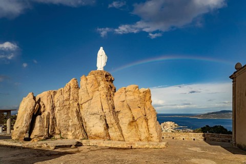 Rainbow on the statue of the Virgin Mary on a rock next to the Notre Dame de la Serra pilgrimage