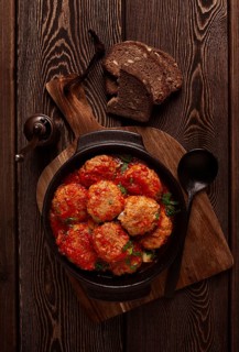 Beef meat balls in tomato sauce, with spices and herbs, on a wooden background, top view, no people