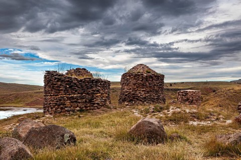Grassy environments with old, stone ruins under clouds, The Chullpas of Sillustani near Puno in