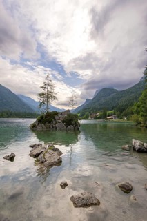 Hintersee with rocks and trees in the foreground, surrounded by mountains after sunset with