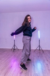 Female dancer practicing choreography in a dance studio illuminated by colorful led lights,
