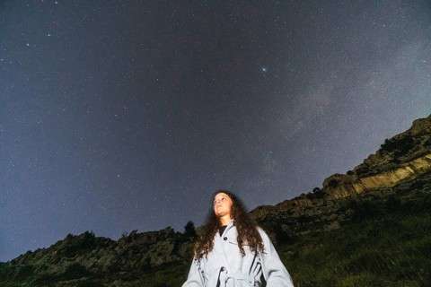 A person stands under a star-filled night sky, surrounded by nature's tranquility A drone captures
