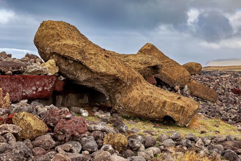A moai in a broken state between rocks and debris on Easter Island, the moai statues on Easter