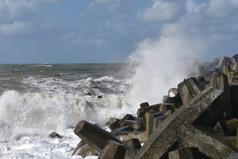 Foaming waves hit rough concrete structures on the coast
