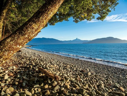 Beach of Pacific Ocean north of Chaiten, peak of Corcovado volcano, Chile