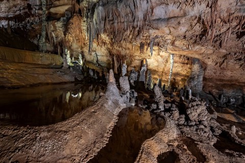 Stalactites and stalagmites, rock formations in a stalactite cave with water basin, Grotta del
