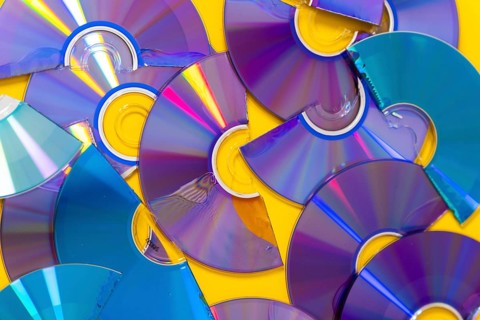 Top view of cut CDs and DVDs against a yellow background