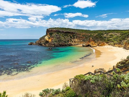 A stunning view of a secluded beach with golden sand, clear turquoise waters, and rocky cliffs