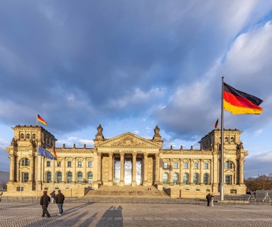 Reichstag building Berlin with German flags. Exterior view with dark clouds. Berlin, Germany