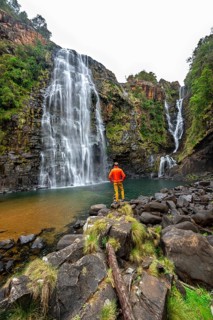 Young man standing in front of a waterfall, Lisbon Falls, long exposure, near Graskop, Mpumalanga,